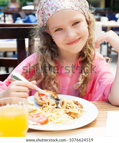 Child eating pasta at cafe