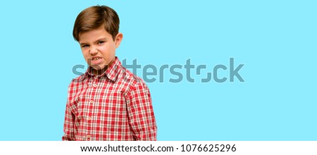 Handsome toddler child with green eyes angry and stressful frowns face in dissatisfaction, irritated and annoyed, expressing anger over blue background