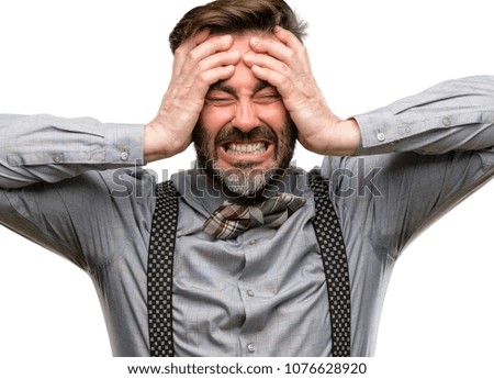 Middle age man, with beard and bow tie stressful keeping hands on head, terrified in panic, shouting isolated over white background