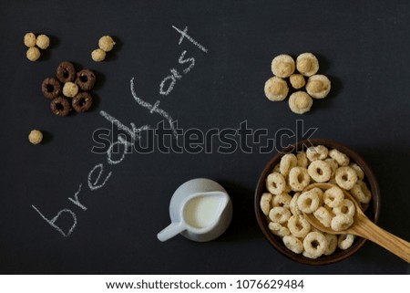 Bowl of Whole Grain Cereal rings with milk on a background of a black chalkboard. top view.