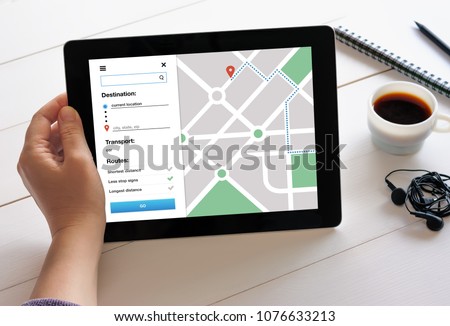 Hand holding digital tablet computer with GPS map navigation app on screen. Location tracker concept
