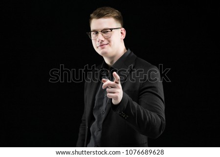 Portrait of confident handsome elegant responsible businessman smiling showing sign on black background
