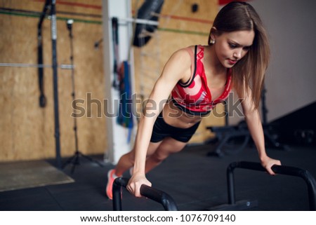 Photo of young woman doing horizontal push-ups with bars