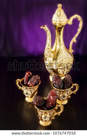 Still life with dates with goldenTraditional Arabic coffee set with dallah and mini cup. Dark background. Vertical photo. Toned photo.