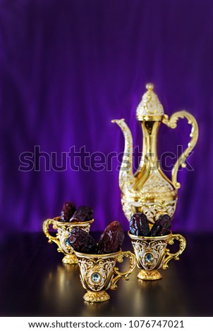 Still life with dates with goldenTraditional Arabic coffee set with dallah and mini cup. Dark background. Vertical photo.