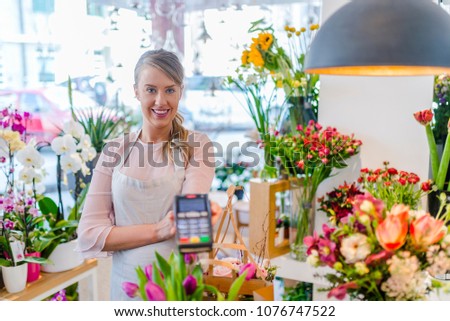 Customer paying with credit card in florist shop. Woman is offering payment terminal for paying with credit card. Florist shop owner holding credit card terminal. Credit card payment