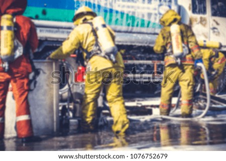 Blurred background. Firemen in firefighter uniform during fire drill and training for safety with foam and chemical fire suppression systems. Backside is fuel tanker truck. Vintage tone.