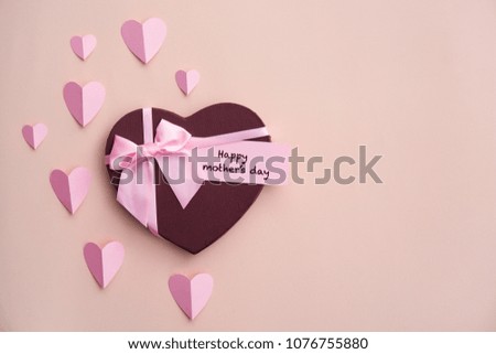 Gift box, paper hearts and greeting card with text "HAPPY MOTHER'S DAY" on color background