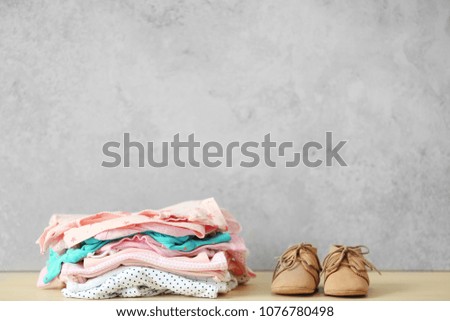 Pile of baby clothes and shoes on table