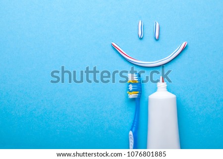 Tooth-paste in the form of face with a smile. Tube of the paste on blue background. Refreshing and whitening toothpaste. Copy space for text Royalty-Free Stock Photo #1076801885