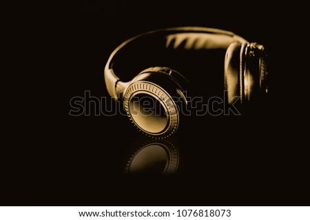 Gold Wireless Headphones on a black background Gold dark tone style. Royalty-Free Stock Photo #1076818073