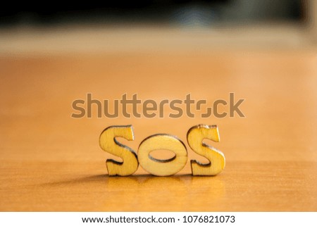The word 'sos' made of wooden letters. wood inscription on table