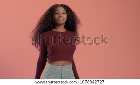 Beauty mixed race african american woman with hair blowed in air smiling at camera dancing On pink background.