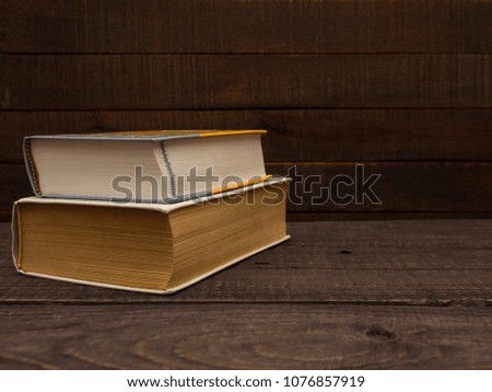 Old and new books lie on a wooden table