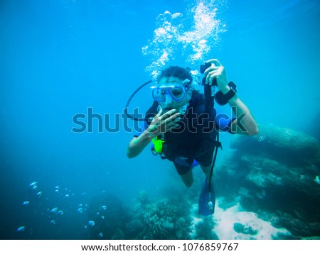 Female scuba diver equalizing the pressure on Oliveli island , Maldives.