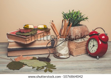 Old books, alarm clock, pencils on a wooden background. Back to school concept