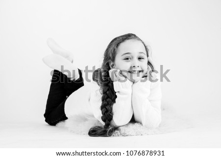 Adorable little girl poses, in sweater and jeans , in studio on white background