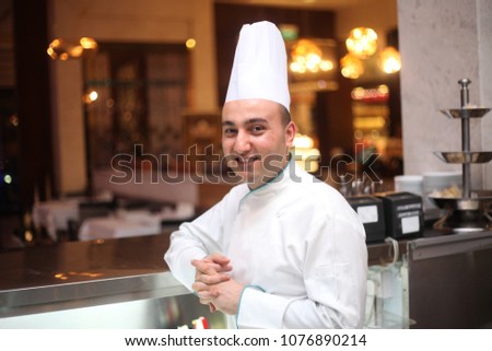 Portrait of a smiling male chef Standing in Kitchen Royalty-Free Stock Photo #1076890214