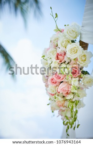 close up fresh pink and white roses decorate the wedding arch blue sky in background 