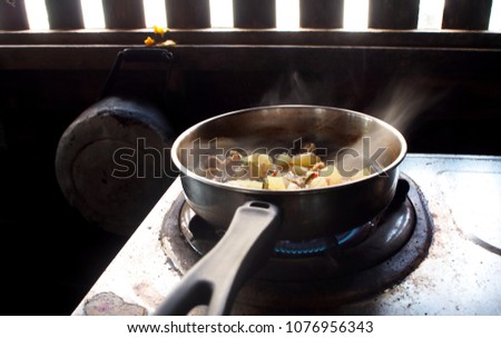 Cook the vegetables and pork in the pan on the gas stove smoke drifting.