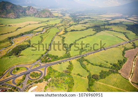 Aerial view of the highway Palín-Escuintla in Guatemala, surroundes by sugar cane fields. On the left is Guacalate River. Royalty-Free Stock Photo #1076960951