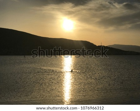 Photo of sunset with golden colors in clear calm water beach