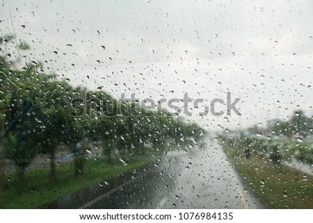 Road view through car window with rain drops driving in the rain, Rainy window in traffic