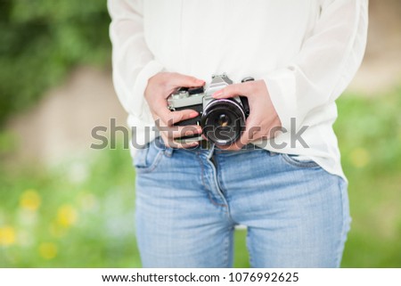 young woman hands holding a camera, view on hands in the garden outdoor, can be used as background