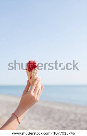 Red ice cream in hand on the sea. Concept of sweet rest.