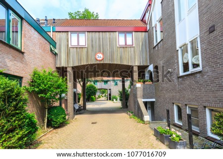 Modern style build residential wooden passageway structure building in a street with homes and houses with a height limt sign.