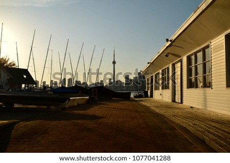 Sunset at the pier looking out at the CN tower with sail boats and skyline in the distance. Sunsetting over Toronto on a beautiful summer evening.