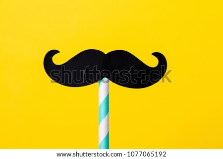 paper mustache on a stick with a turquoise stripe on a yellow background Royalty-Free Stock Photo #1077065192