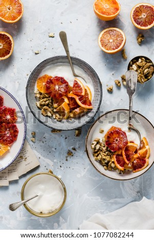 Delicious healthy breakfast - yoghurt with red oranges, walnuts and honey served on a blue texture blog style