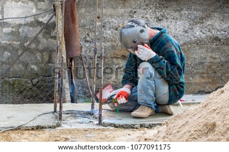 An unknown welding worker on the construction of a private house. Problems of labor migration. Illegal labor migration. Observance of safety in construction. Royalty-Free Stock Photo #1077091175