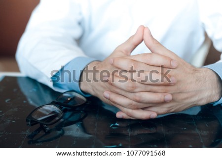 folded hands of the doctor lie on the table on the mri shot diagnosis