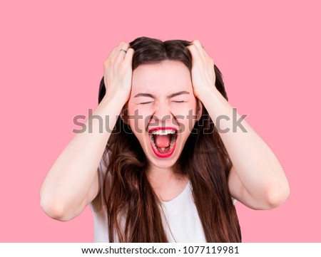 An angry woman is holding her hair and screaming. Stress at work and a nervous breakdown, isolated picture