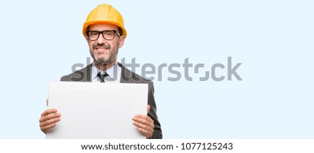 Senior architect or engineer holding blank advertising banner, good poster for ad, offer or announcement, big paper billboard isolated over blue background