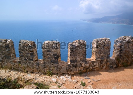 Fragment of the fortress wall overlooking the sea. These are the so-called teeth of the fortress wall. Fortress of Alanya in Turkey. Royalty-Free Stock Photo #1077133043