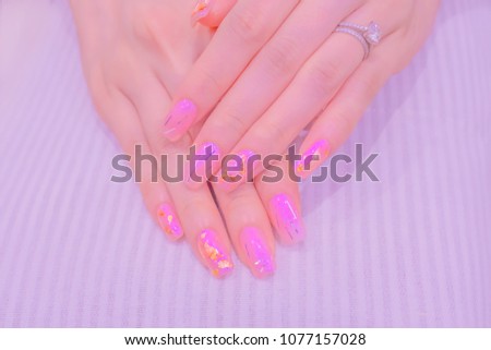 closeup sweet beautiful romantic shimmer pink gel polish decorated with silver and gold sparkling gritter on artificial acrylic nail fashion woman doing manicure hand care