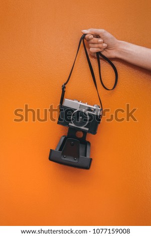 Hand holding a Vintage camera isolated at orange wall