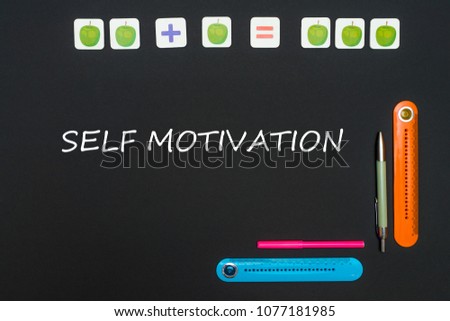 Concept school, black art table with stationery supplies with text self motivation on blackboard