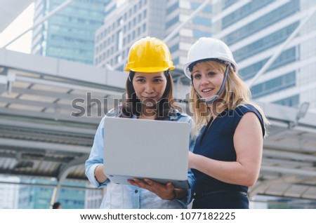 attractive woman architecture and woman engineer together working at outdoor with laptop on working site.