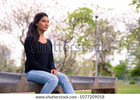 Portrait of young beautiful Persian woman relaxing at the park in Bangkok, Thailand