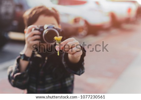 Young boy taking photos of yellow flower in his hand on vacation in Cinematic color