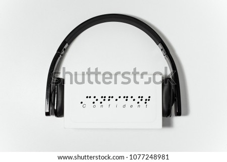 The confident word type with Braille text on the white box under the black headset.