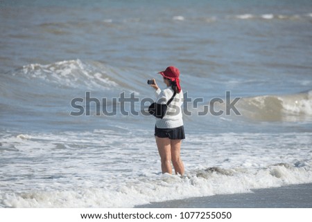 unknown woman stops to take a picture of the waves while on vacation