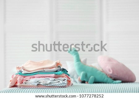 Pile of baby clothes on bed