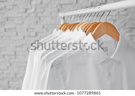 Rack with clean clothes on hangers after dry-cleaning indoors Royalty-Free Stock Photo #1077289865