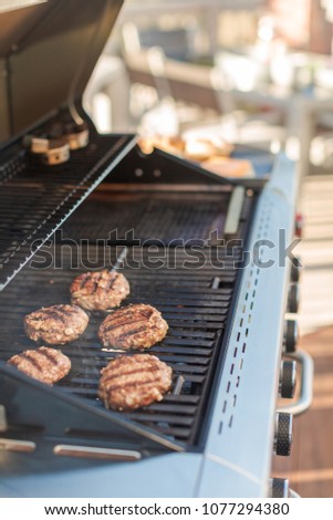 Grilling classic burgers on outdoor gas grill in the Summer.