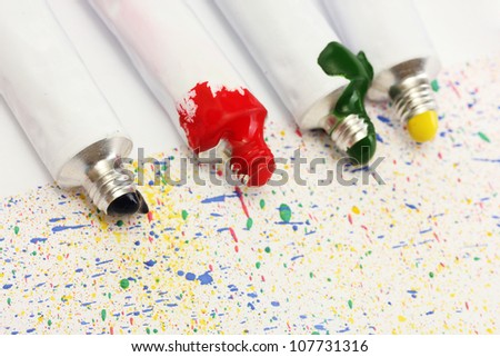Tubes with colorful watercolors on colorful splash background close-up